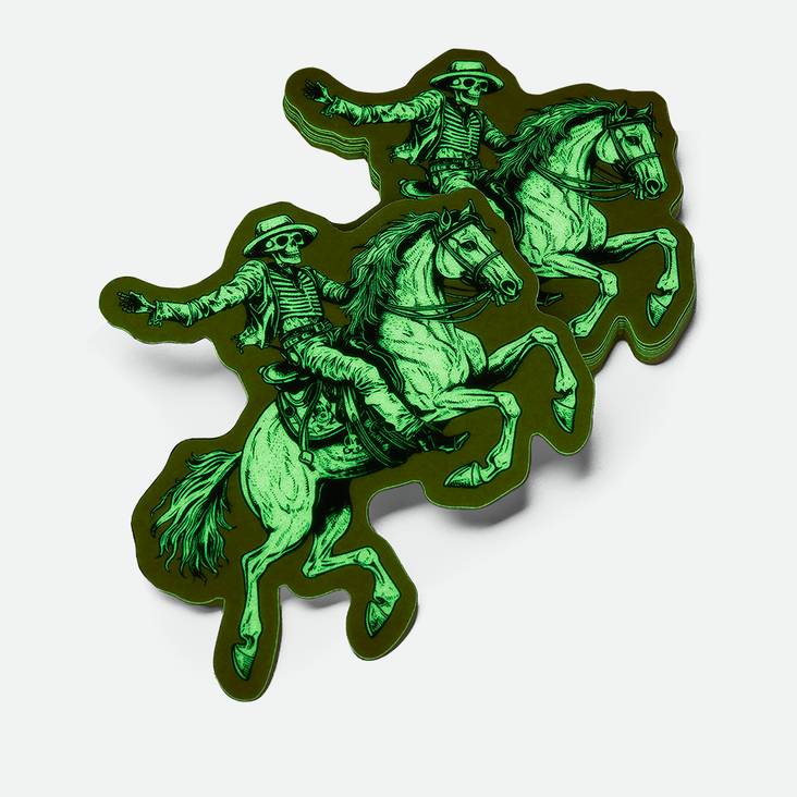 A stack of glow in the dark stickers printed by StickerGiant in the shape of a skeleton riding a horse