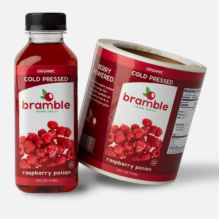 A roll of glossy labels printed by StickerGiant with a bottle of juice with the Bramble cold pressed juice glossy label applied to the bottle