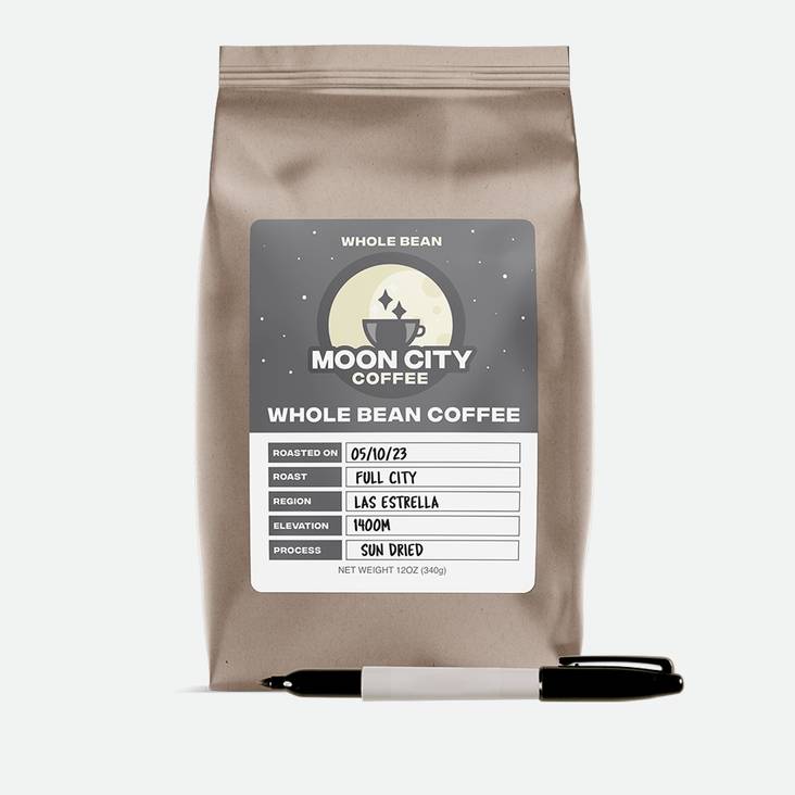 A bag of coffee with a Moon City whole bean coffee matte paper label printed by StickerGiant applied to the side of the bag