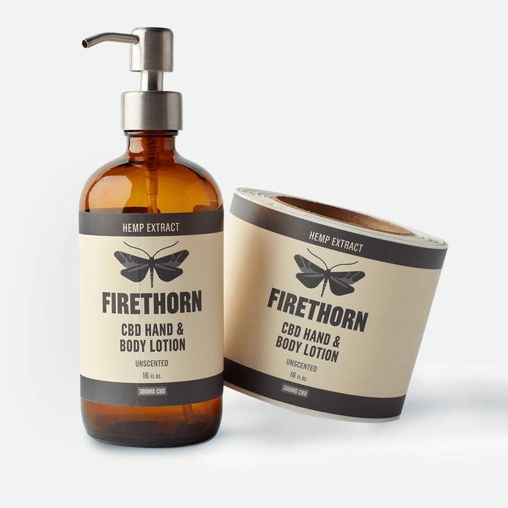 A roll of Firethorn matte paper labels printed by StickerGiant next to a lotion bottle with matte paper label applied to the bottle